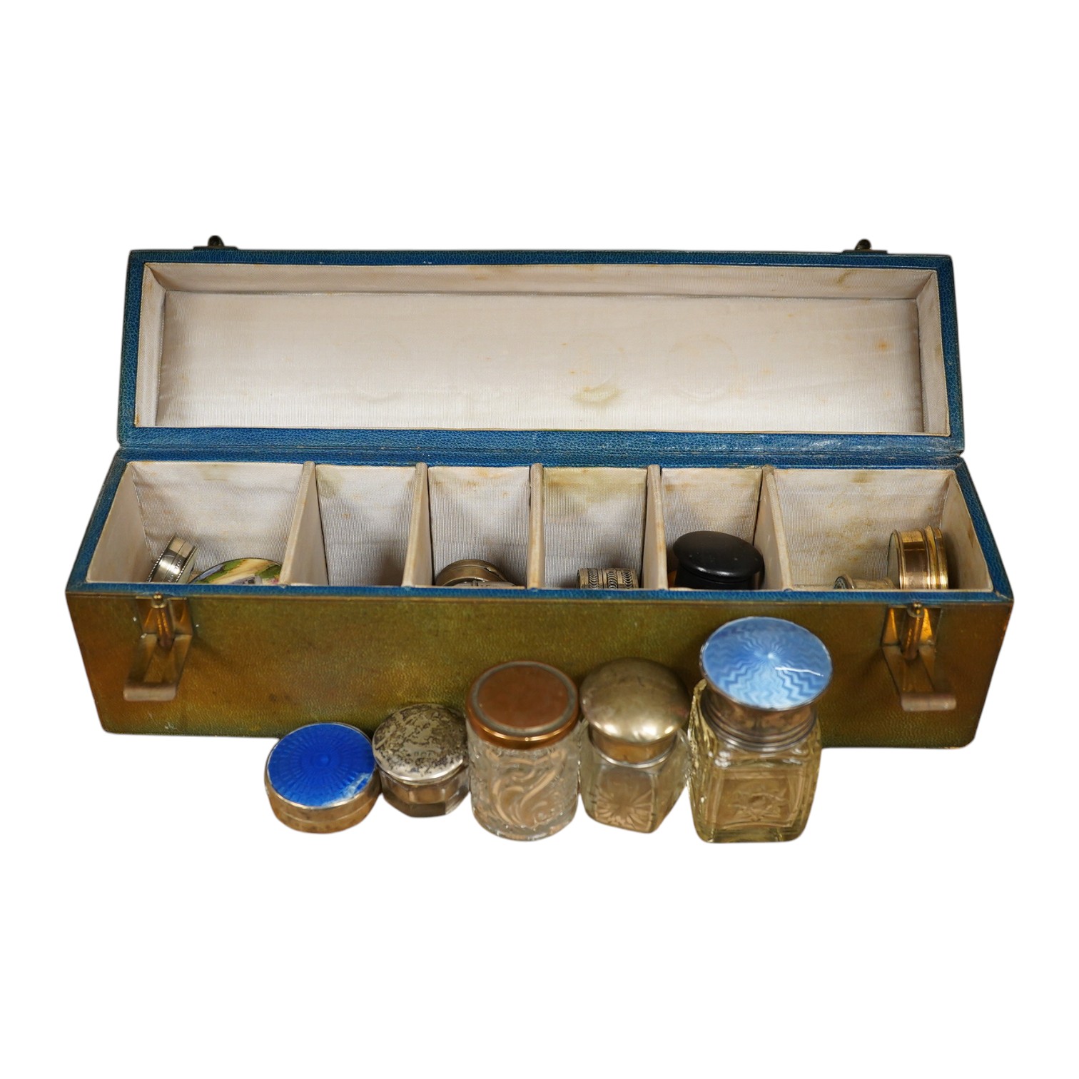 A green leather sectioned box containing a collection of cut glass, silver mounted and silver plated boxes and jars, some with guilloche enamel lids, largest 7cm high